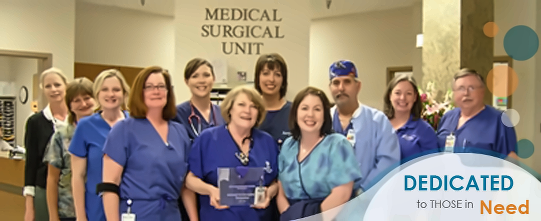 Hospital staff in scrubs beneath a "Medical Surgical Unit" sign